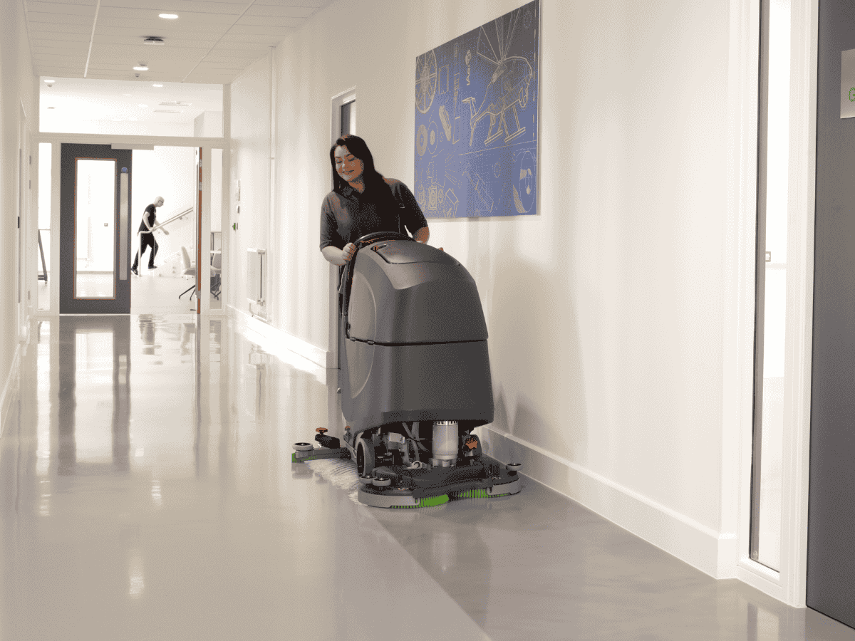 Szorowarka TBL8572 prowadzona czyszcząca korytarz w obiekcie przemysłowym operator prowadzi maszynę